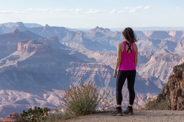 Naklejka premium Adventurous Traveler standing on Desert Rocky Mountain American Landscape. Cloudy Sunny Sky. Grand Canyon National Park, Arizona, United States. Adventure Travel