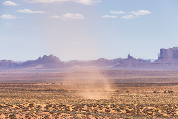 Dust Devil on a hot sunny day in a desert with red rocky mountains in background. Oljato-Monument...