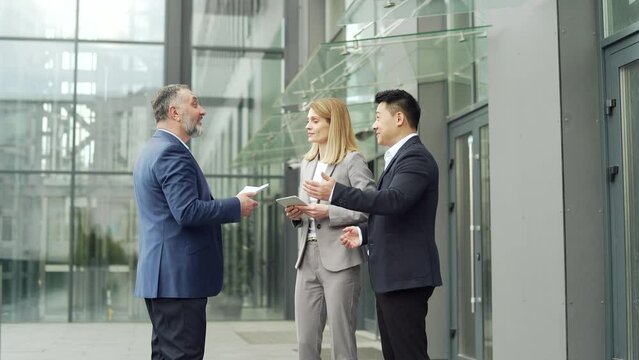 meeting of business team partners outside. Negotiations of a group of business people shaking hands, getting to know each other, discussing a project near an office building diverse employees in suit