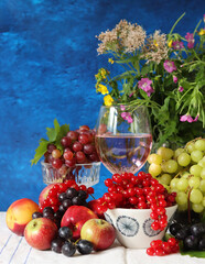Glass of pink wine, grapes, berries and flowers on a table. Delicious summer food close up photo. Textured background with copy space.
