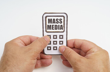In the hands of a person is a cardboard model of a telephone with an inscription on the screen - mass media