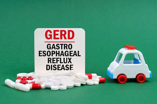 On A Green Surface, An Ambulance, Pills And A White Sign With The Inscription - Gastro Esophageal Reflux Disease