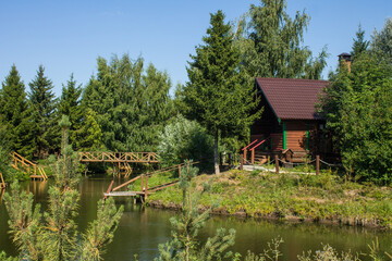 Wooden Russian hut on the shore of a pond with a reflection on a sunny summer bright day in Suzdal russia