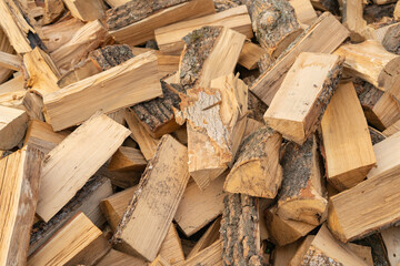 Dry sawn and chopped firewood in a pile under the open sky. Creative vintage background.