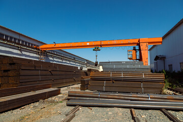 Gantry crane transporting stack of metal pipes