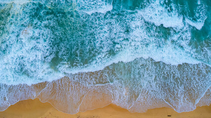 Beautiful sea waves and white sand beach in the tropical island. Soft waves of blue ocean on sandy beach background from top view from drones. Concept of relaxation and travel on vacation.