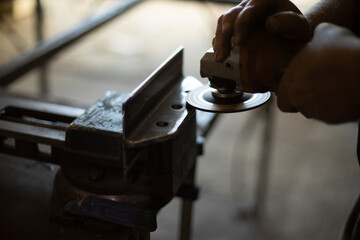 Grinding steel. Worker grinds metal. Work in garage. Electric tool in hand.