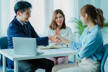 Obraz premium Group of happy young Asian businesswomen shaking hands congratulating success. Excited and happy with the work done. And encourage the team members by holding hands happily.