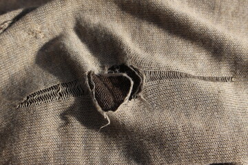 Hole in clothing or piece of cloth. Concept for tattered or torn clothes, mending clothes,...