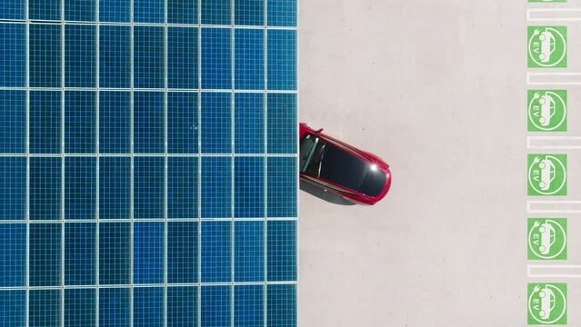 Innovative technology 4K aerial footage. Overhead view on modern red electric vehicle backing up. Charged car from the renewable natural source of sun energy generated in solar batteries, EV charging