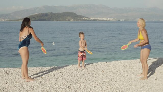 Slow motion video of a family playing tennis and bambinton by the ocean. Beach sports active games, mom and baby playing together. High quality 4k footage