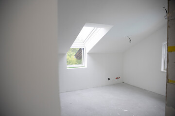 modern attic construction site freshly painted, the floor is still screed, walls are white