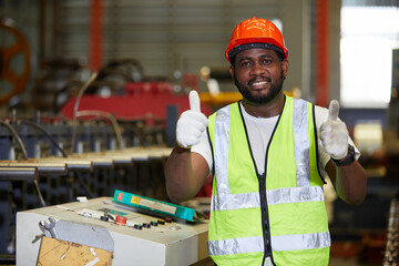African factory worker or engineer smiling and thumbs up pose in metal sheet factory - Powered by Adobe