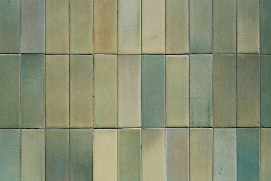Texture and pattern of a green ceramic wall tiles, grunge square mosaic close up, background, retro facade of the building.