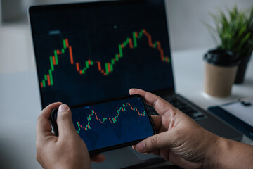 Close up of hands trading stock on laptop and phone for marketing money in office space.