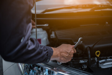 Male mechanic is checking the car maintenance lists for maintenance and fixing the car.