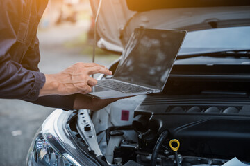 Male mechanic is checking the car maintenance lists for maintenance and fixing the car.