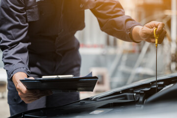 Male mechanic is checking the car maintenance lists for maintenance and fixing the car.