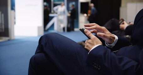 Close up of male executive hands working on his cellphone at conference centre