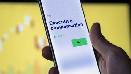 An investor's analyzing the executive compensation etf fund on screen. A phone shows the ETF's prices stocks to invest - obrazy, fototapety, plakaty