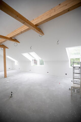 modern attic construction site freshly painted, the floor is still screed, walls are white