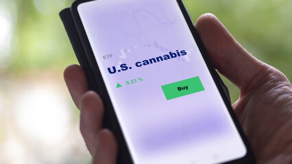 An investor's analyzing the U.S. cannabis etf fund on screen. A phone shows the ETF's prices u.s., u.s.a. marijuana to invest