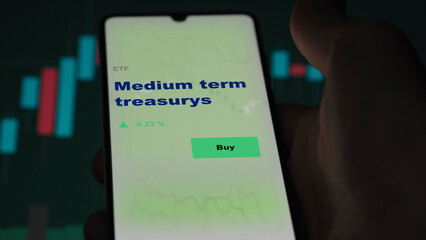 An investor's analyzing the medium treasuries on screen. A phone shows the ETF's prices medium term treasury