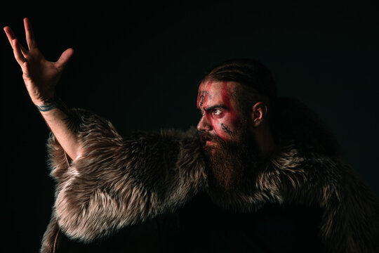 Viking warrior with war paint and fur raising his hand to the sky