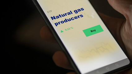 An investor's analyzing the  on screen. A phone shows the ETF's prices natural gas producers