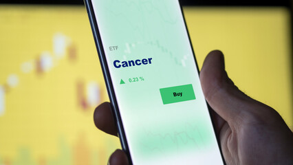 An investor's analyzing the  on screen. A phone shows the ETF's prices cancer