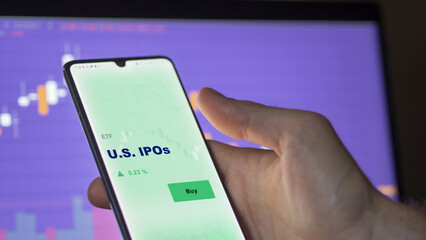 An investor's analyzing the u.s., u.s.a.ipo on screen. A phone shows the ETF's prices U.S. IPOs