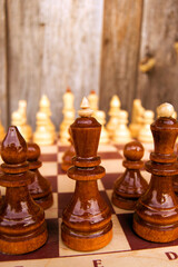 Close-up of chess pieces on a wooden background on a sunny day. Concept: board game and intellectual activity