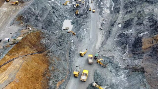 Excavator working on at open pit mining on amazing sunset background. Backhoe digs sand and gravel in quarry. Heavy construction equipment during excavation at construction site
