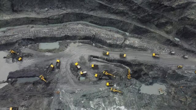 Excavator working on earth moving at open pit mining on amazing sunset background. Backhoe digs sand and gravel in quarry. Heavy construction equipment during excavation at construction site