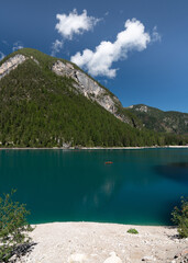 Lots of wooden boats in a picturesque, blue Braies lake.Logo di Braies Pragser Wildsee in Italy.  Alps. Dolomites mountains in South Tyrol Coniferous forest. Blue sky . Tourist place. High mountains.