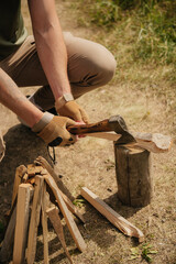 Camping outdoors leisure concept: male hands prepare and chop firewood at fireplace with axe hatchet 