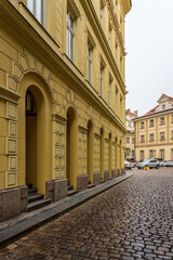 Obraz premium A yellow building on the edge of a cobbled street.