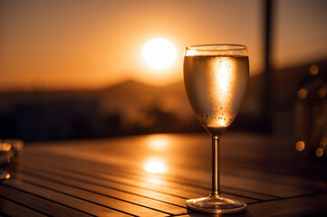 Traditional house white wine served in tavern, traditional greece drink, mazing sunset as background