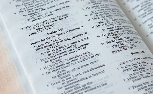 Psalm 147 verses in an open Holy Bible Book, a closeup. Praise of God's care for Jerusalem, a Christian biblical concept.