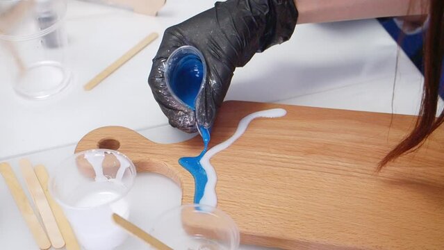 Epoxy resin art. Imitation of the sea. Sea foam. Modern trendy hobby. The pouring process of a wooden. Decorative cutting board. Master carpenter fills a wooden board with epoxy resin. Blue and white
