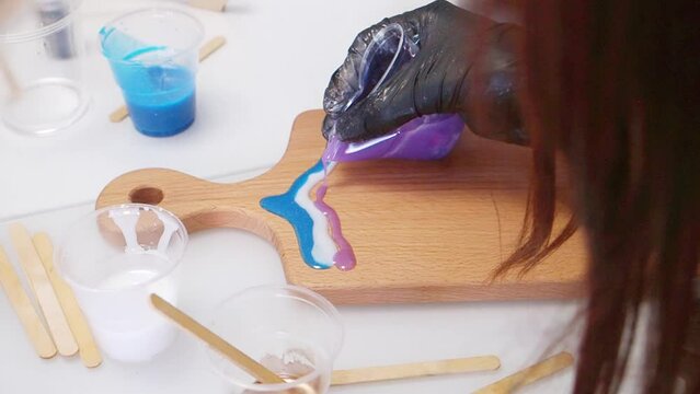 Epoxy resin art. Imitation of the sea. Sea foam. Modern trendy hobby. The pouring process of a wooden. Decorative cutting board. Master carpenter fills a wooden board with epoxy resin. Blue and white