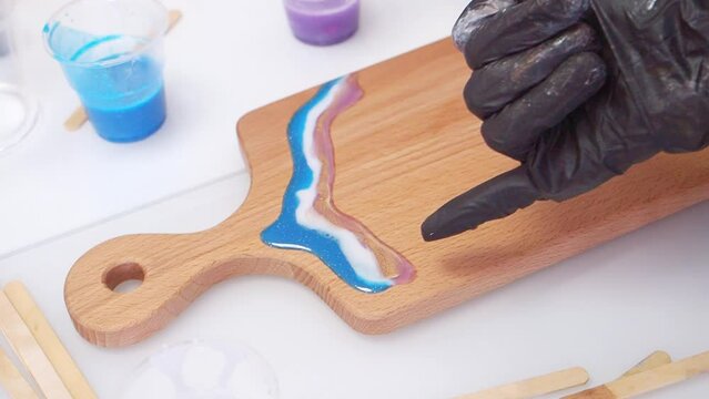 Epoxy resin art. Imitation of the sea. Sea foam. Modern trendy hobby. The pouring process of a wooden. Decorative cutting board. Warming up the resin with a burner
