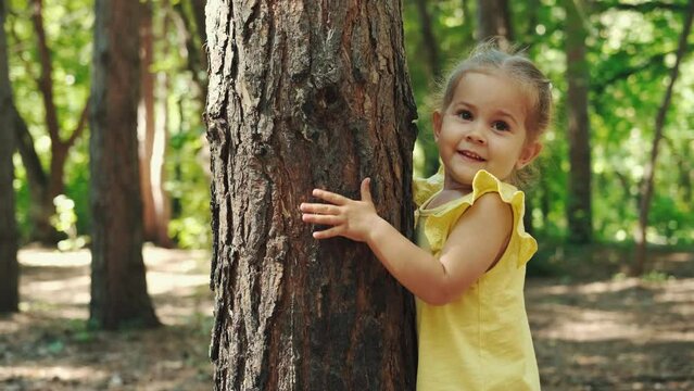 A 2-year-old child hugs a tree trunk in the forest.Earth Day, Save Planet, Save the world, Love Nature.