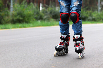 roller skates on the legs of a boy with protection on his knees, riding on the street on asphalt