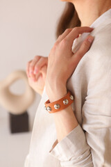 leather studded brown bracelet on woman hand closeup photo on white wall background