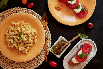 Italian pasta fusilli, caprese salad - tomato, basil, mozzarella and pesto in low key. Bread...
