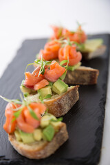 Salmon trout bruschetta on bread pieces with avocado and micro greens snack food