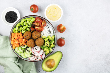 Poke bowl: rice, falafel, avocado,tomatoes,beans, cucumbers. Buddha bowl: rice, falafel, vegetables on gray background.