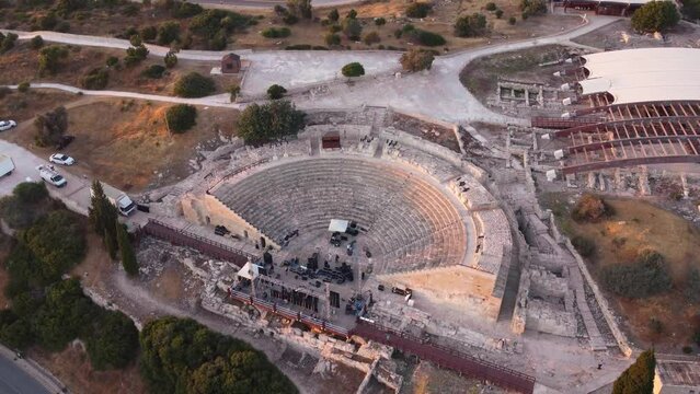 Aerial drone footage of archaeological site of ancient Kourio city  in Limassol district, Cyprus. 360 orbital view of the theatre forming a semicircle,greek roman ruins, beach at sunset from above.