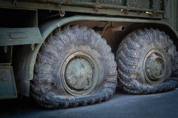 Fototapeta na wymiar Flat tires on old military equipment. Fragment of a broken army car